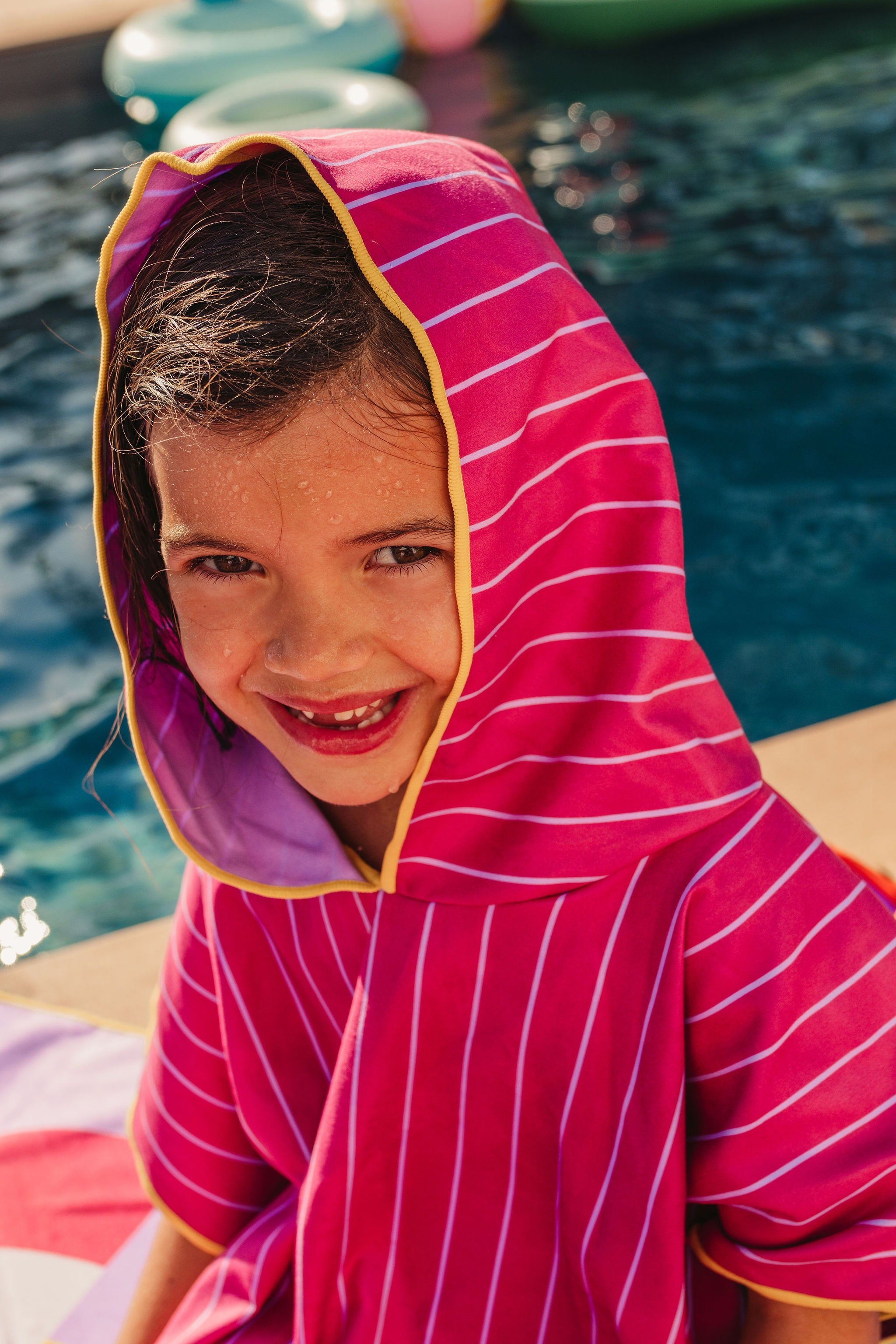 Child wearing burgundy hooded beach poncho after swimming lightweight quick-dry towel