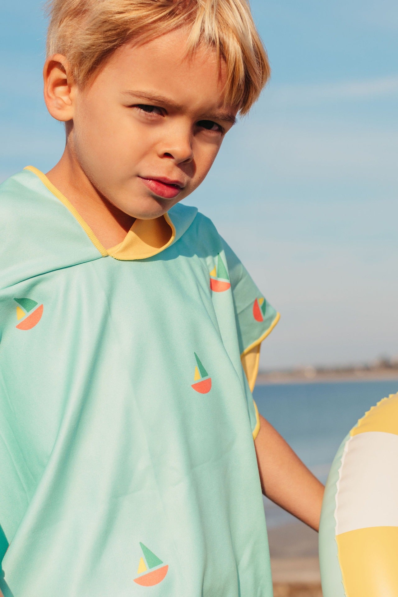 Child wearing blue hooded beach poncho after swimming lightweight microfibre towel