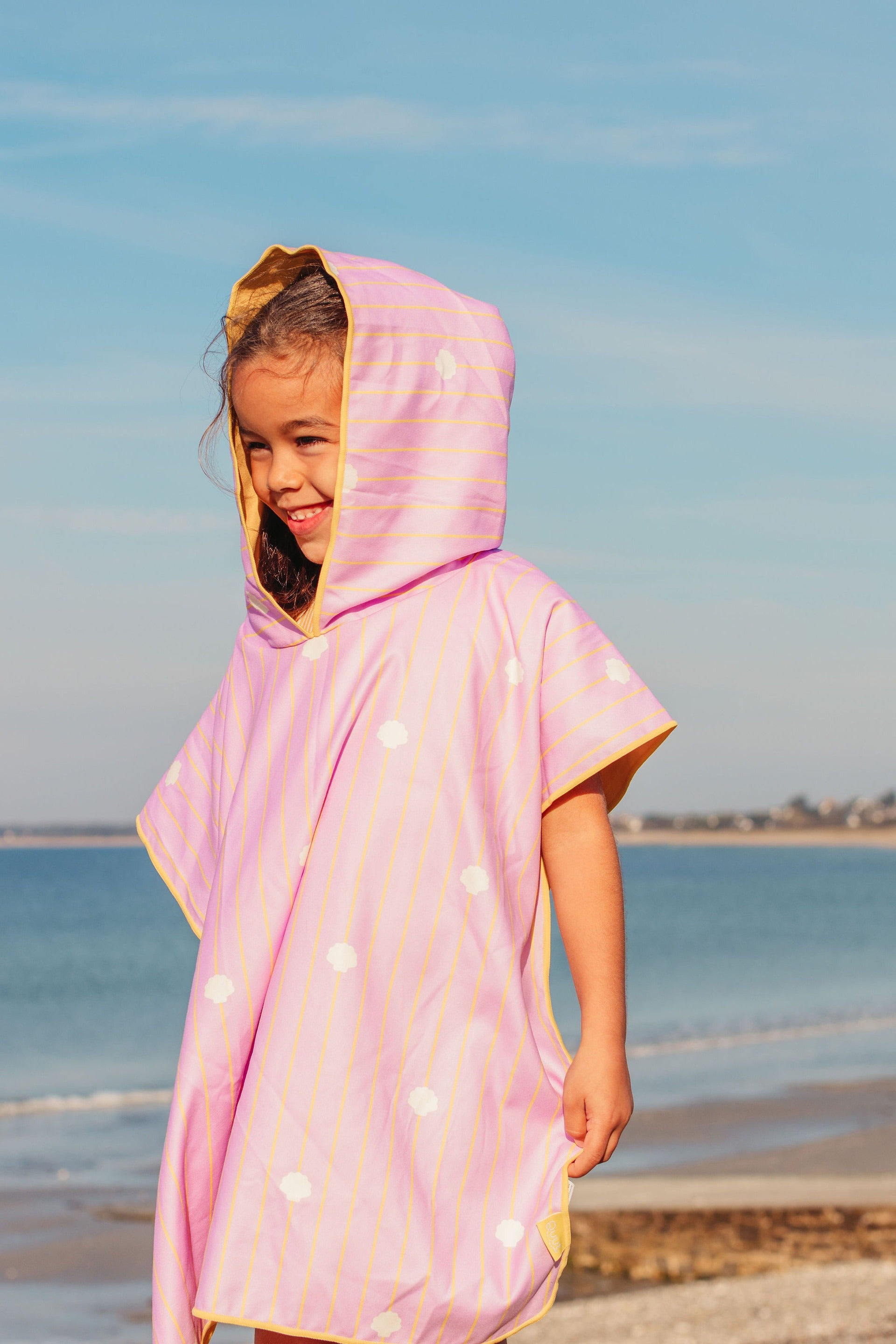 Child wearing pink hooded beach poncho after swimming lightweight quick-dry towel